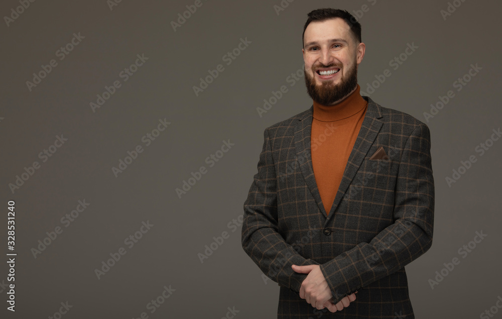 Fototapeta premium Handsome young bearded man on grey background looking at camera. Portrait of laughing young man.