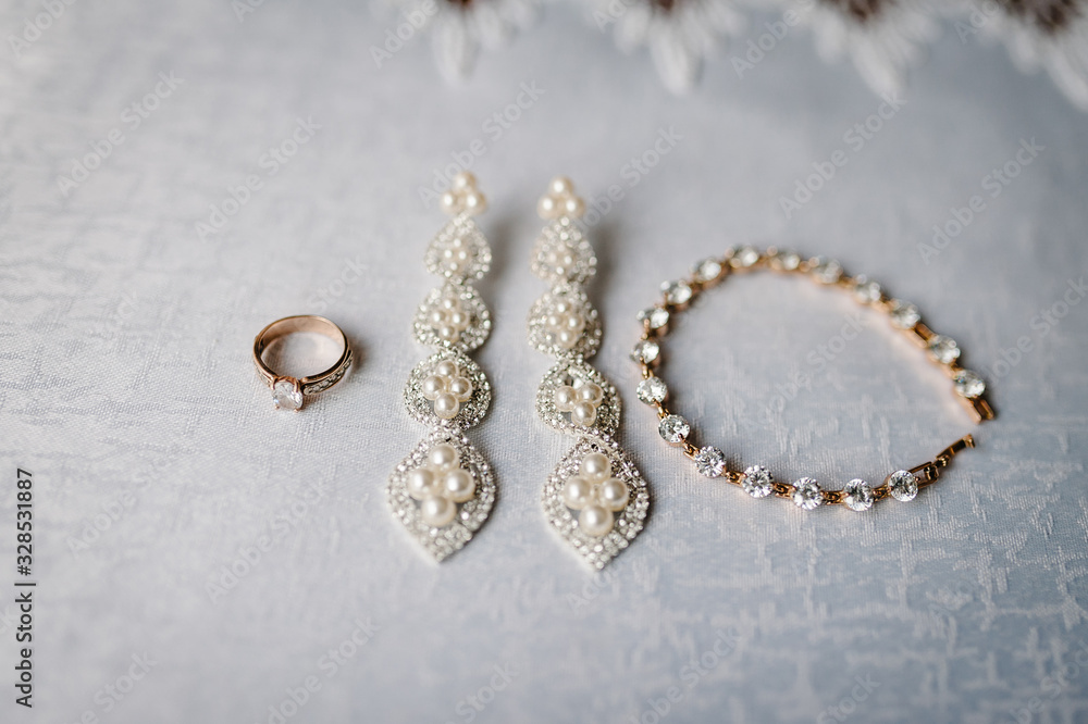 Set of fine gold jewelry with pearls with precious stones. Wedding accessory bride. Stylish earrings, chain, gold ring on table standing on white background. flat lay. top view. Set of fine gold jewelry with pearls with precious stones. Wedding accessory bride. Stylish earrings, chain, gold ring on table standing on white background. flat lay. top view.