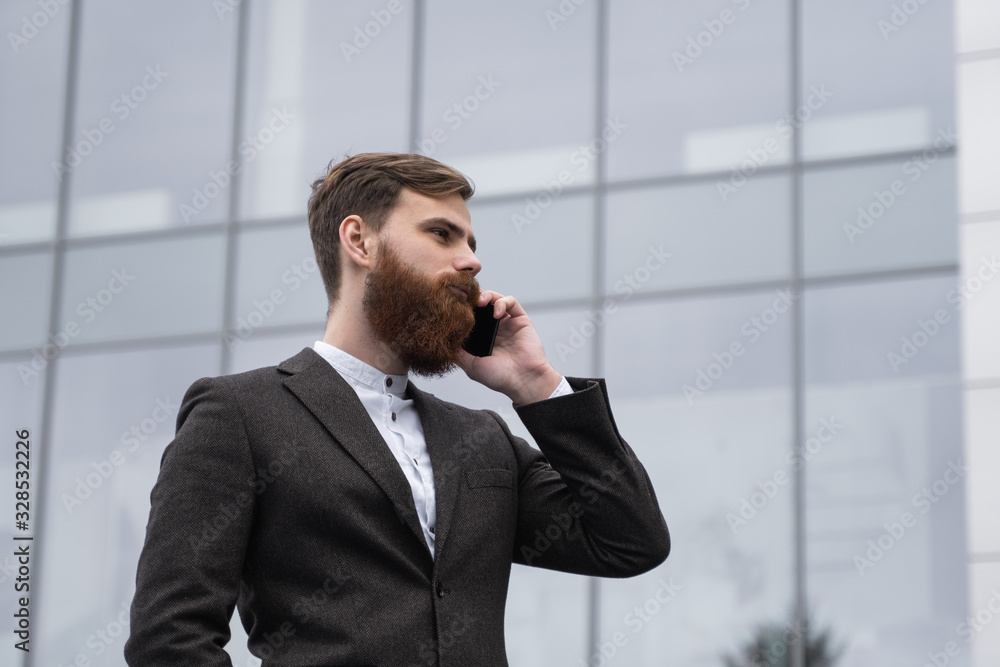 Businessman talking on the phone in financial district. Portrait of a Young urban professional man using smart phone over office building. Business man talking on his smartphone outdoors. Technology. Businessman talking on the phone in financial district. Portrait of a Young urban professional man using smart phone over office building. Business man talking on his smartphone outdoors. Technology.