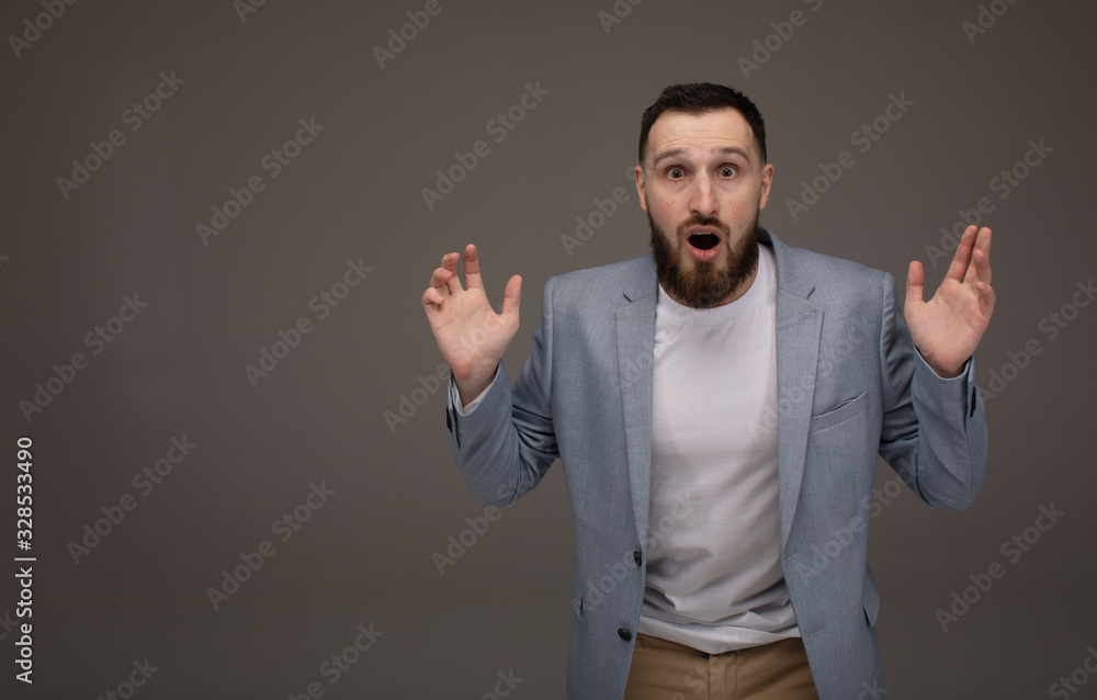 Portrait of young man with shocked and surprised facial expression face on grey background Portrait of young man with shocked and surprised facial expression face on grey background