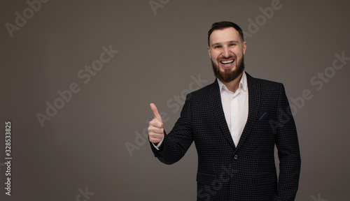 Happy businessman thumbs up sign on grey background