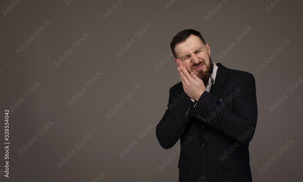 Close up portrait of nervous unhappy troubled handsome bearded man touching his cheek he has toothache isolated on gray background. Close up portrait of nervous unhappy troubled handsome bearded man touching his cheek he has toothache isolated on gray background.
