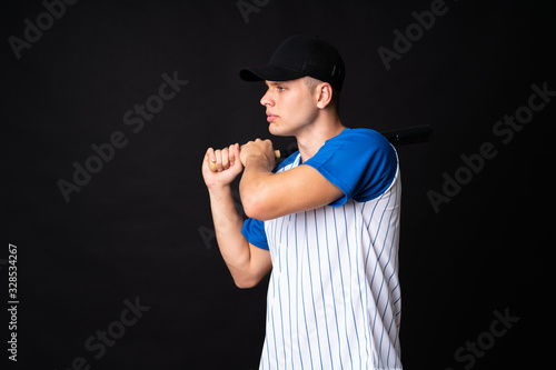 Young man playing baseball over isolated black background
