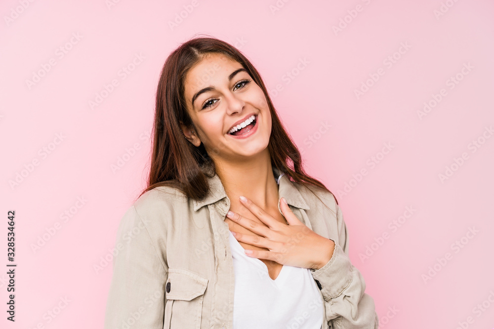 Young caucasian woman posing in a pink background laughs out loudly keeping hand on chest. Young caucasian woman posing in a pink background laughs out loudly keeping hand on chest.