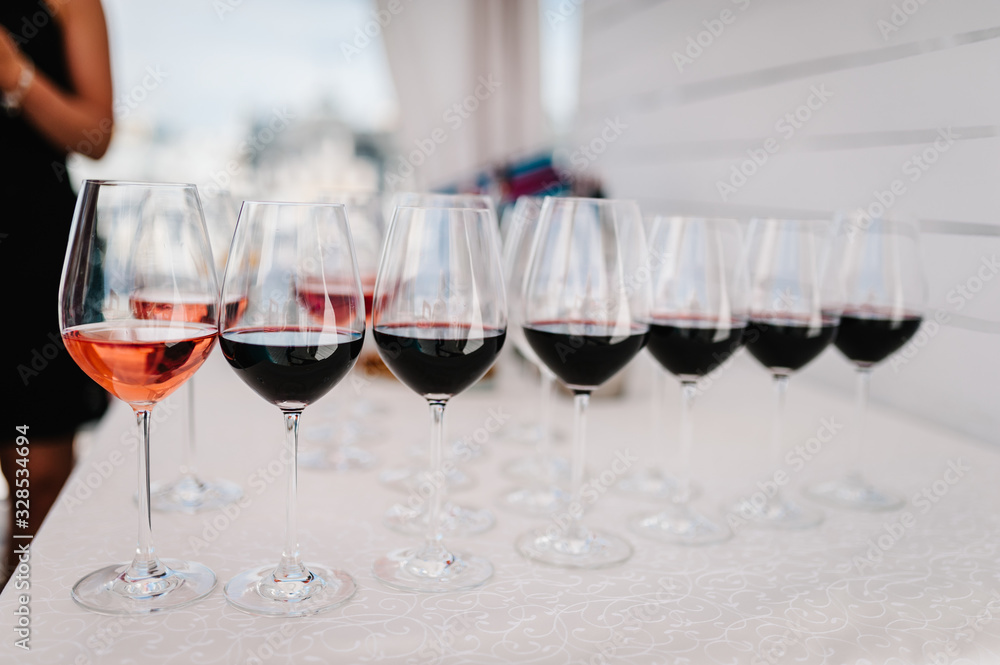 Many glass of red wine on a table near bar counter. Glasses with wine. Filled with half and stand on the holiday table. Furshet. selective focus.