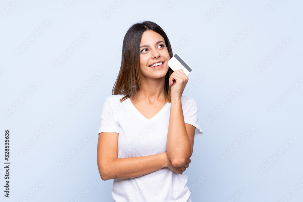 Young woman over isolated blue background holding a credit card Young woman over isolated blue background holding a credit card