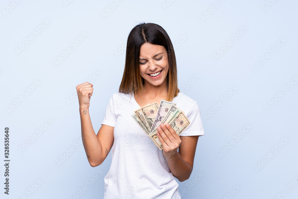 Young woman over isolated blue background taking a lot of money Young woman over isolated blue background taking a lot of money