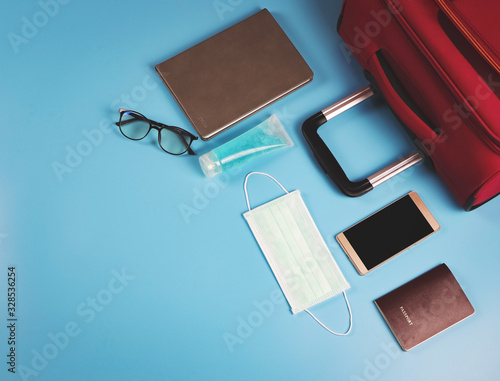  flat lay of business traveling accessories with face mask and sanitizer  on blue background ,protection from corona virus or COVID-19 during traveling concept with copy space