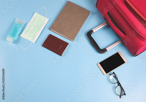 Top view or flat lay of business traveling accessories with face mask and sanitizer  on blue background ,protection from corona virus or COVID-19 during traveling concept with copy space