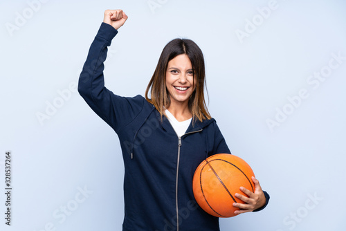 Young woman over isolated blue background with ball of basketball © luismolinero