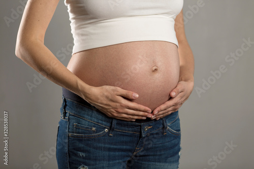 Big belly of a pregnant woman on a gray background. Close-up.