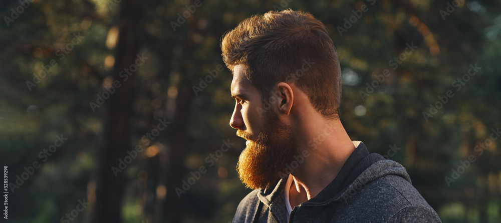 Close up portrait of confident bearded man in a autumn park. Profile young handsome serious bearded man Young hipster hiking forest. - obrazy, fototapety, plakaty 