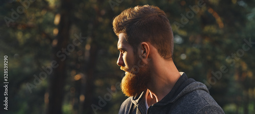 Close up portrait of confident bearded man in a autumn park. Profile young handsome serious bearded man Young hipster hiking forest.