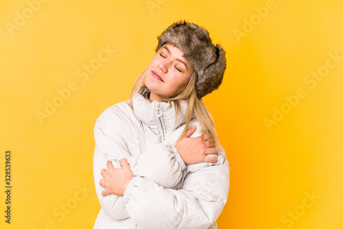 Young caucasian woman wearing a winter clothes isolated hugs, smiling carefree and happy. © Asier