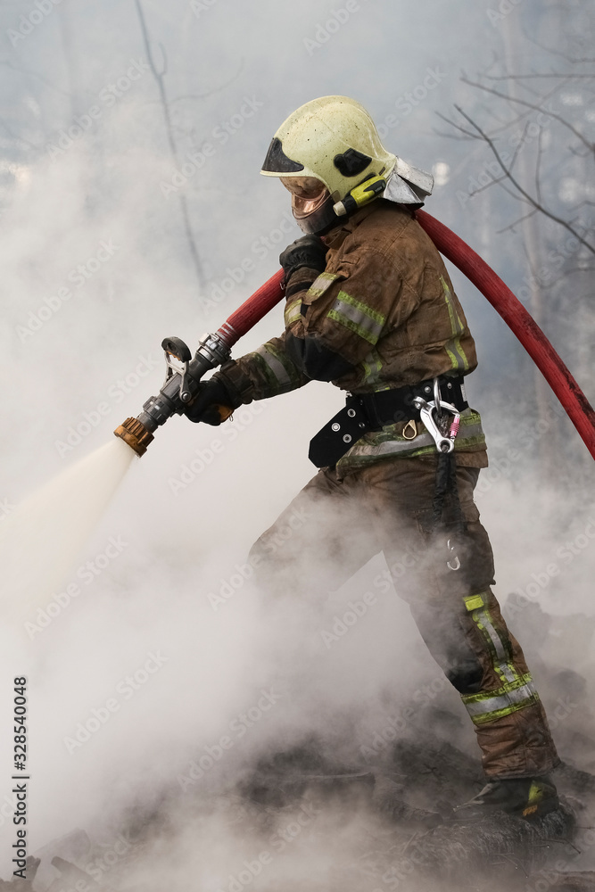 Brave firefighter saving burning building. Firefighter work concept. Firefighter are using water in fire fighting operation. Real brave hero combat the fire Brave firefighter saving burning building. Firefighter work concept. Firefighter are using water in fire fighting operation. Real brave hero combat the fire