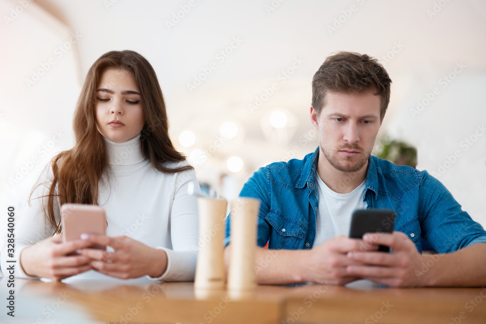 young couple beautiful woman and handsome man sitting at cafe during coffee break, both holding smartphones, digital influence concept young couple beautiful woman and handsome man sitting at cafe during coffee break, both holding smartphones, digital influence concept