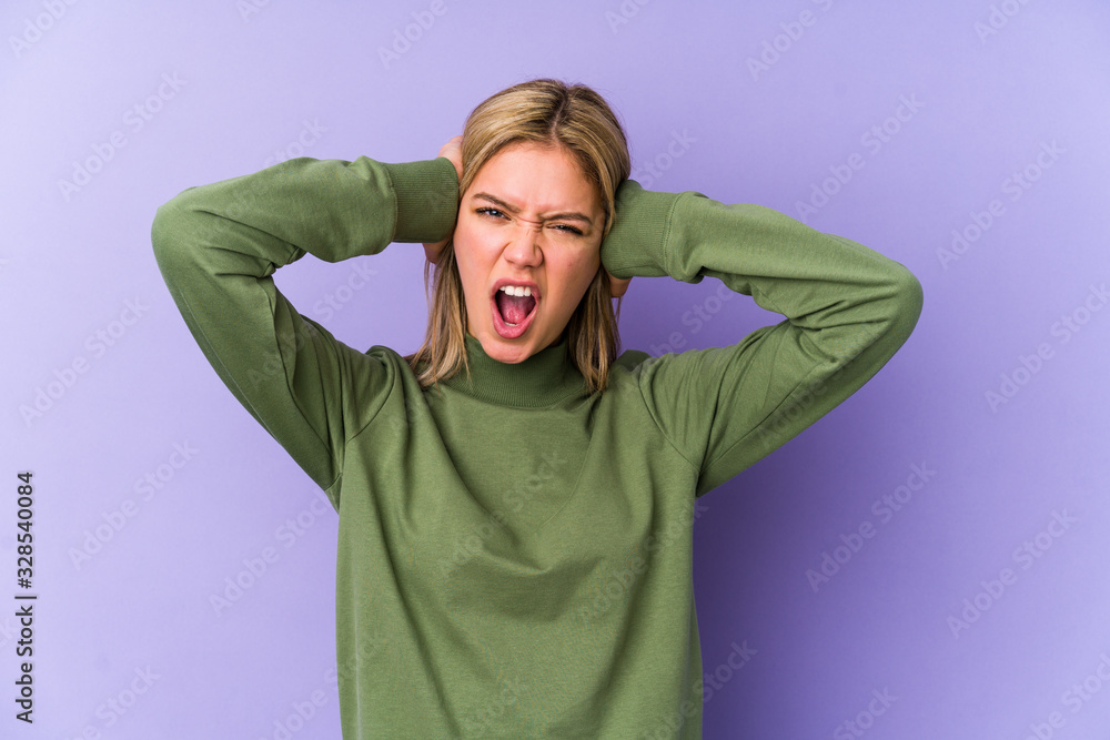 Young blonde caucasian woman isolated covering ears with hands trying not to hear too loud sound. Young blonde caucasian woman isolated covering ears with hands trying not to hear too loud sound.