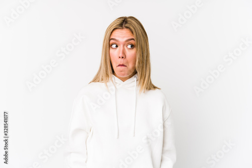 Young blonde caucasian woman isolated shrugs shoulders and open eyes confused.