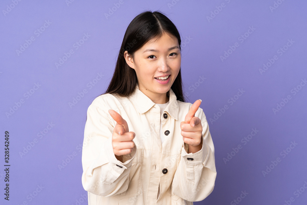 Young asian woman isolated on purple background surprised and pointing front Young asian woman isolated on purple background surprised and pointing front