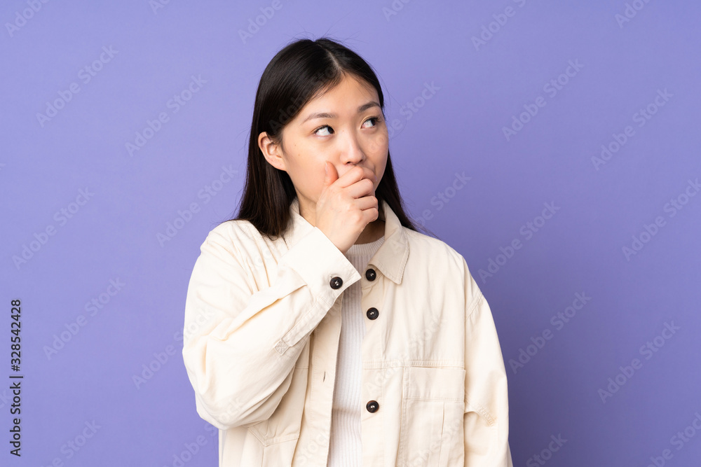 Young asian woman isolated on purple background having doubts and with confuse face expression Young asian woman isolated on purple background having doubts and with confuse face expression