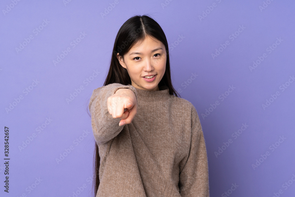 Young asian woman isolated on purple background pointing front with happy expression Young asian woman isolated on purple background pointing front with happy expression