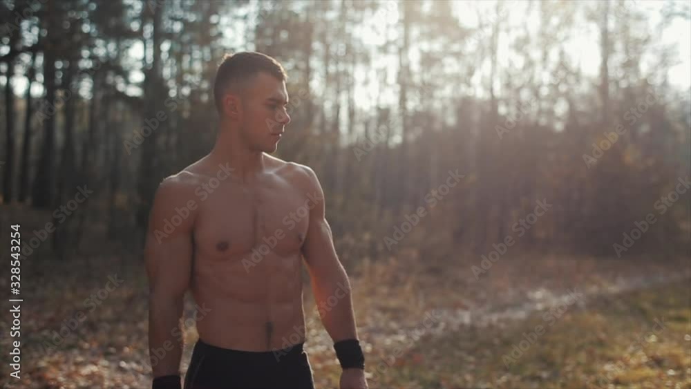 Portrait of muscular sportsman with naked torso in the park. Slow motion Portrait of muscular sportsman with naked torso in the park. Slow motion
