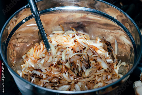 Fried onion for barbecue sausages in stainless big bowl. Close up shot. BOQ picnic outside in park. photo