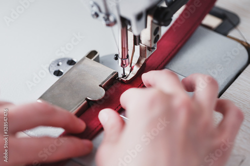 Bild auf Leinwand A leather craftsman produces leather goods on a sewing machine in his shop