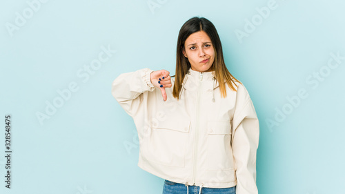 Fotografie, Tablou Young woman isolated on blue background showing thumb down, disappointment concept