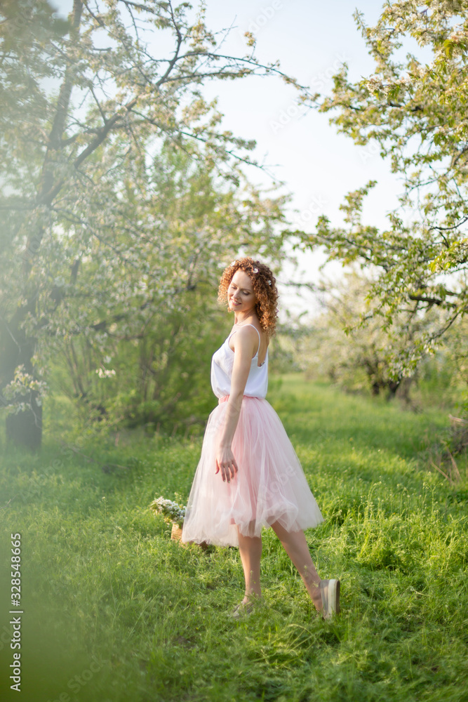 Young attractive girl walks in spring green park enjoying flowering nature Young attractive girl walks in spring green park enjoying flowering nature