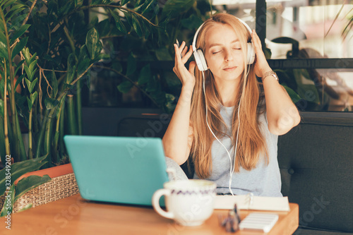Girl with a laptop listens to music through headphones. High tech modern digital concept
