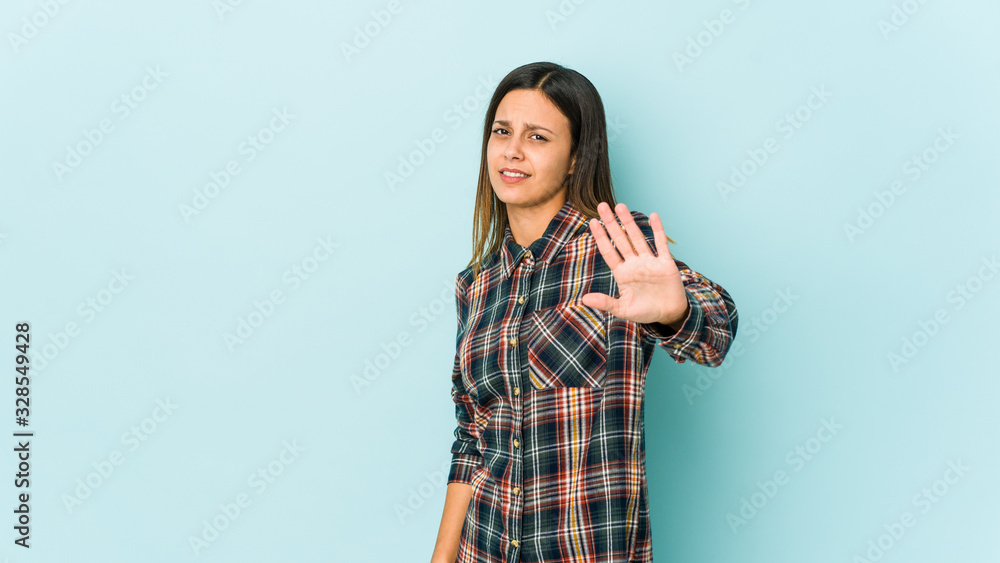 Young woman isolated on blue background rejecting someone showing a gesture of disgust. Young woman isolated on blue background rejecting someone showing a gesture of disgust.