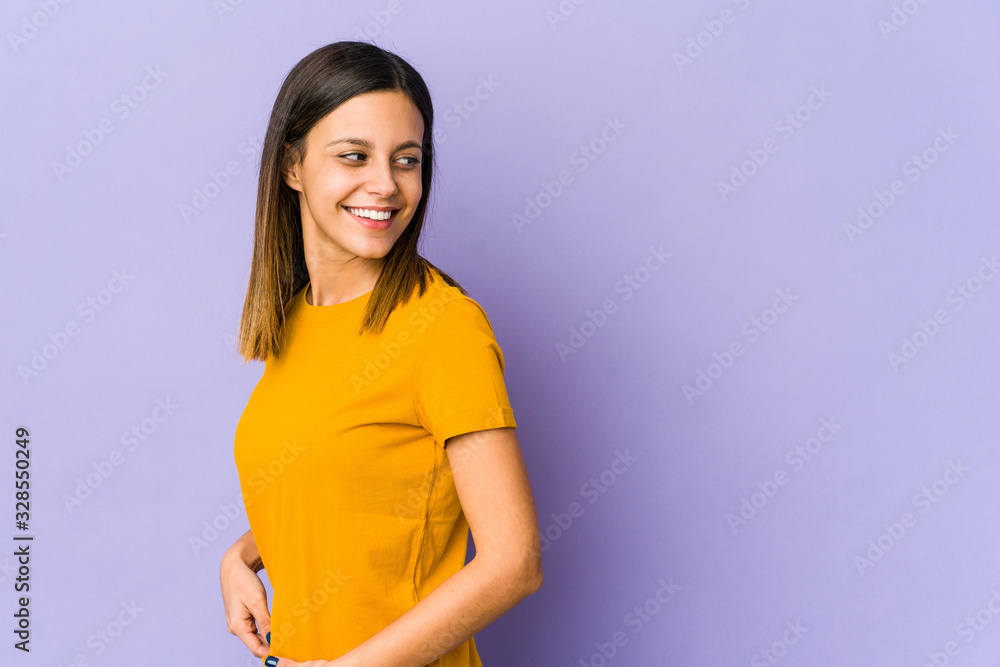 Young woman isolated on purple background looks aside smiling, cheerful and pleasant. Young woman isolated on purple background looks aside smiling, cheerful and pleasant.