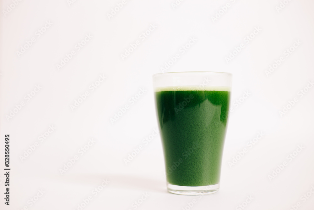 green freshly squeezed juice of green Apple and young spinach leaves on a white background green freshly squeezed juice of green Apple and young spinach leaves on a white background