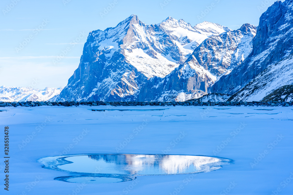 Winter landscape with snow covered peaks and frozen lake on Kleine Scheidegg mountain in Swiss Alps in Grindelwald ski resort, Switzerland