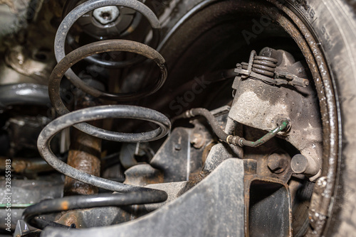 Rear car suspension from below, visible suspension springs, shock absorber and braking system