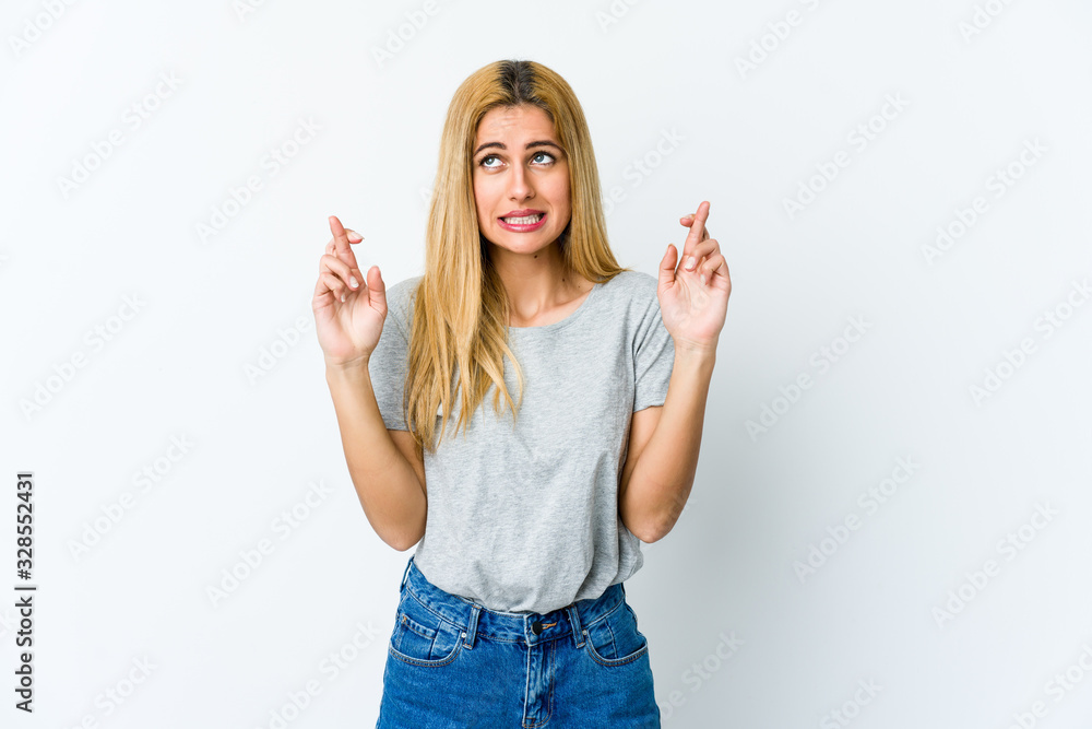 Young blonde woman isolated on white background crossing fingers for having luck Young blonde woman isolated on white background crossing fingers for having luck