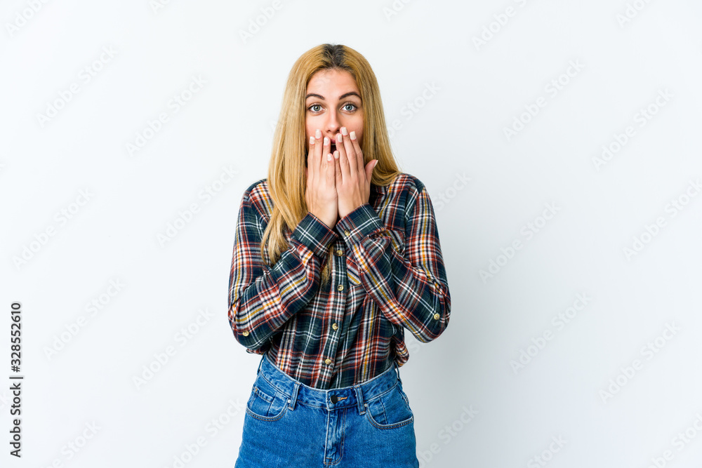 Young blonde woman isolated on white background shocked, covering mouth with hands, anxious to discover something new. Young blonde woman isolated on white background shocked, covering mouth with hands, anxious to discover something new.