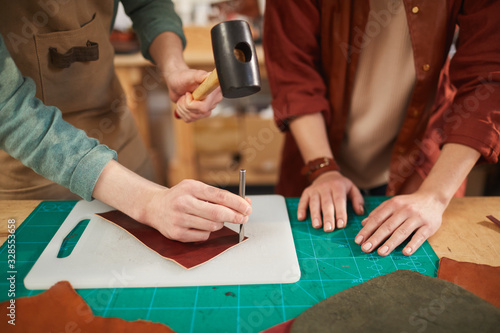 Hands of unrecognizable man and woman working together in modern leather craft workshop, copy space