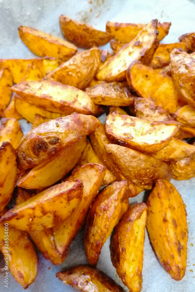 Baked potato wedges on parchment paper. Baked potato wedges on parchment paper.