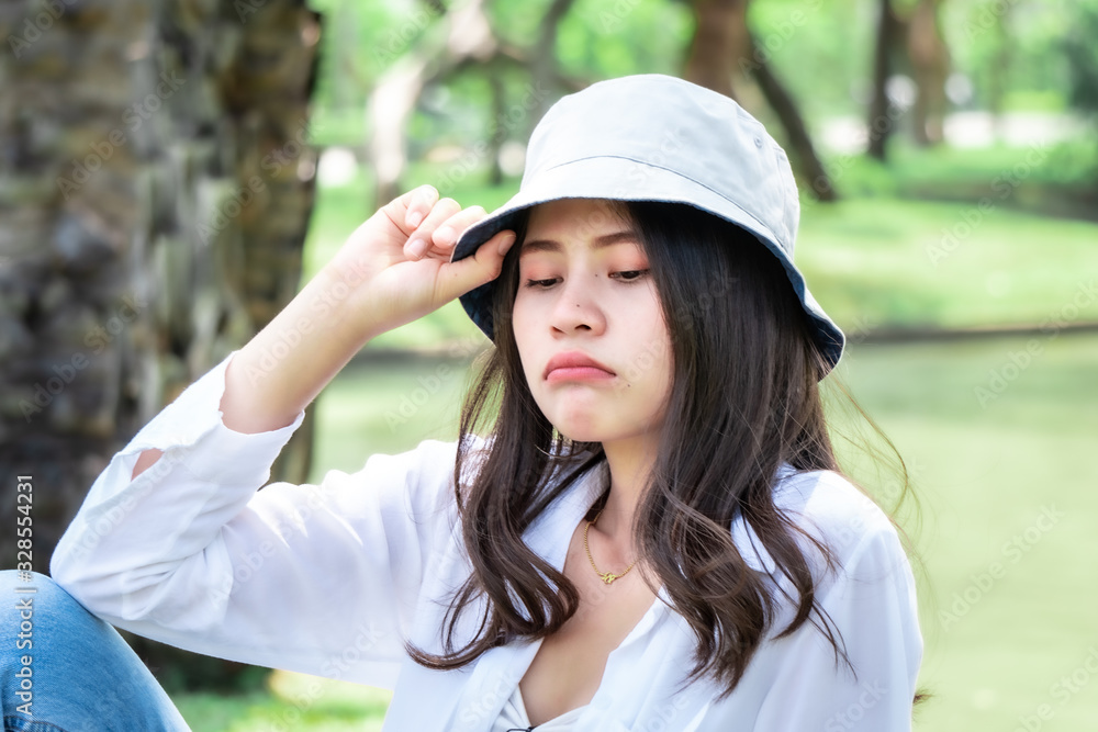 Beautiful Asian women with long hair wearing a white shirt. White bug hat, jeans showing emotions In the nature park Beautiful Asian women with long hair wearing a white shirt. White bug hat, jeans showing emotions In the nature park