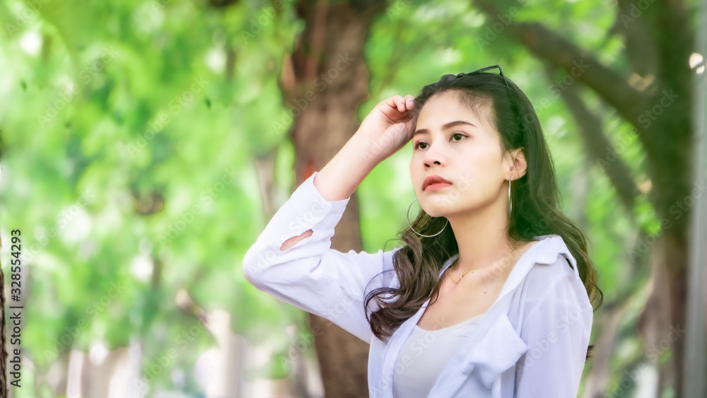 Beautiful Asian women with long hair wearing a white shirt. White bug hat, jeans showing emotions In the nature park Beautiful Asian women with long hair wearing a white shirt. White bug hat, jeans showing emotions In the nature park