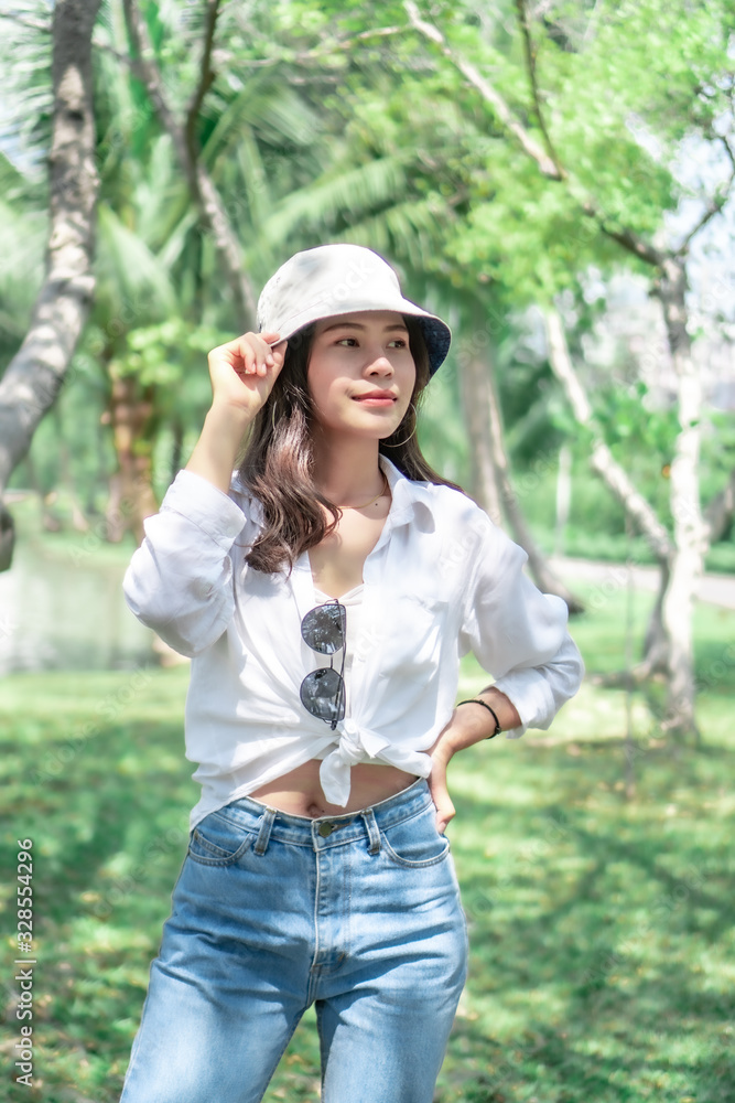 Beautiful Asian women with long hair wearing a white shirt. White bug hat, jeans showing emotions In the nature park Beautiful Asian women with long hair wearing a white shirt. White bug hat, jeans showing emotions In the nature park