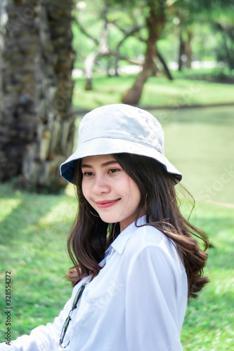 Beautiful Asian women with long hair wearing a white shirt. White bug hat, jeans showing emotions In the nature park
