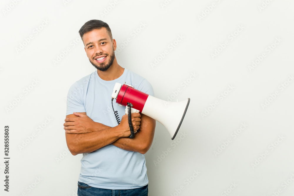 Young mixed race asian man holding a megaphone smiling confident with crossed arms. Young mixed race asian man holding a megaphone smiling confident with crossed arms.