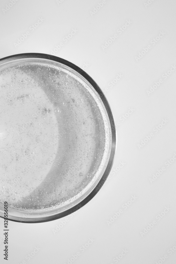Close-up transparent shower gel in glass petri dish on white background. Cosmetic texture, above Close-up transparent shower gel in glass petri dish on white background. Cosmetic texture, above