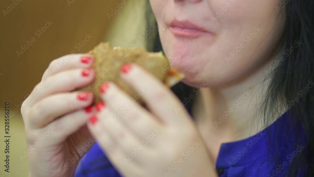 Woman with an appetite eats a burger at lunch Woman with an appetite eats a burger at lunch