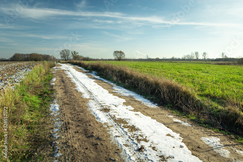 Last snow on a dirt road on a sunny day, rural view photo