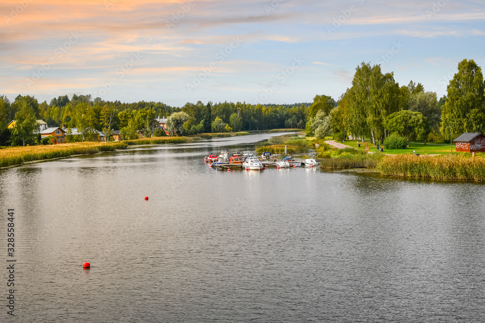 A colorful sky as the sun sets over boats, dock, homes and a park along the Porvoonjoki River in Porvoo, Finland.