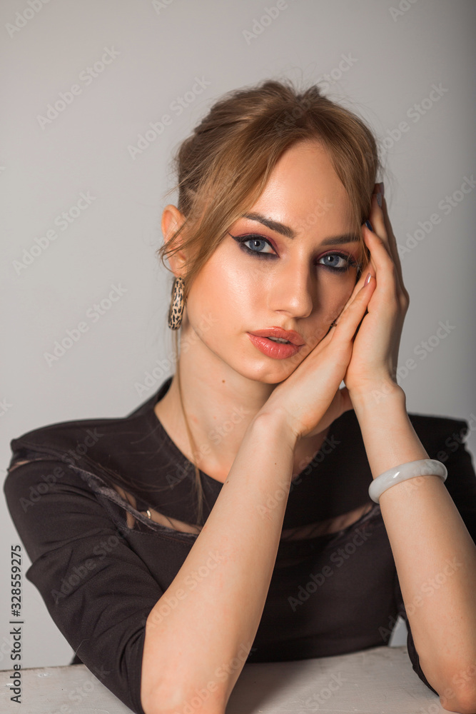 beautiful young woman with make-up in black clothes on a gray background beautiful young woman with make-up in black clothes on a gray background